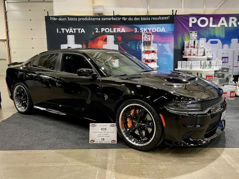 Blanksvart Dodge Charger SRT Hellcat från 2016 i en monter med Autoglym-produkter och skylten Tvätta, polera, skydda.