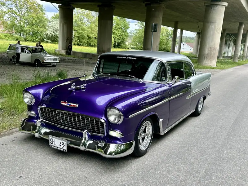 Lila Chevrolet Bel Air med silverfärgat tak parkerad under en motorvägsbro.