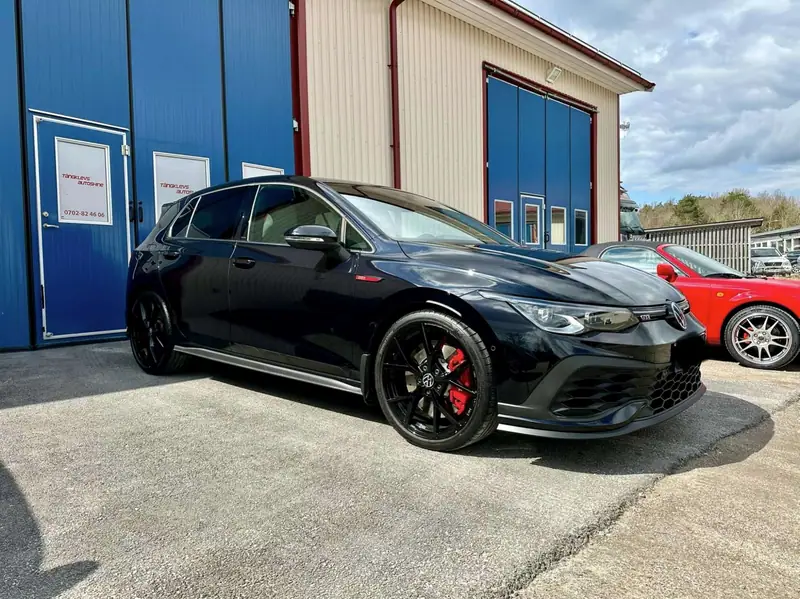 Svart Volkswagen Golf med röda bromsok utanför verkstaden.