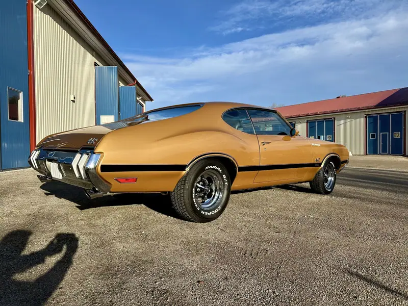 Guldfärgad Oldsmobile 442 snett bakifrån med blanka kromstötfångare.