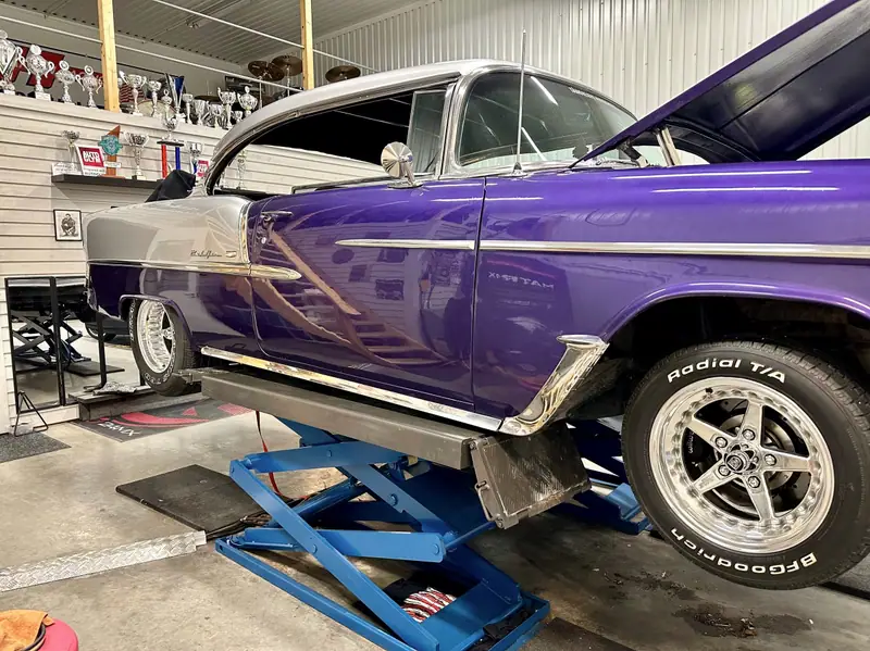 Lila Chevrolet Bel Air på en lyft, sedd snett framifrån med blank lack, kromlister och breda däck.