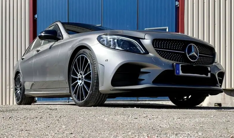 Silverfärgad Mercedes-Benz C-klass fotograferad lågt framifrån framför verkstaden.
