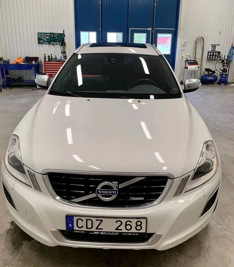 Vit Volvo XC60 rakt framifrån i verkstaden.