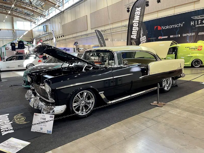 Svart och gul Chevrolet Bel Air från 1955 med öppen motorhuv i en monter på Bilsport Performance & Custom Motor Show.