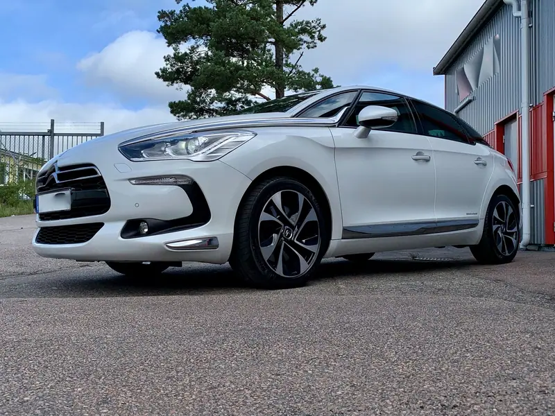 Vit Citroën DS5 med svart tak utanför verkstaden.