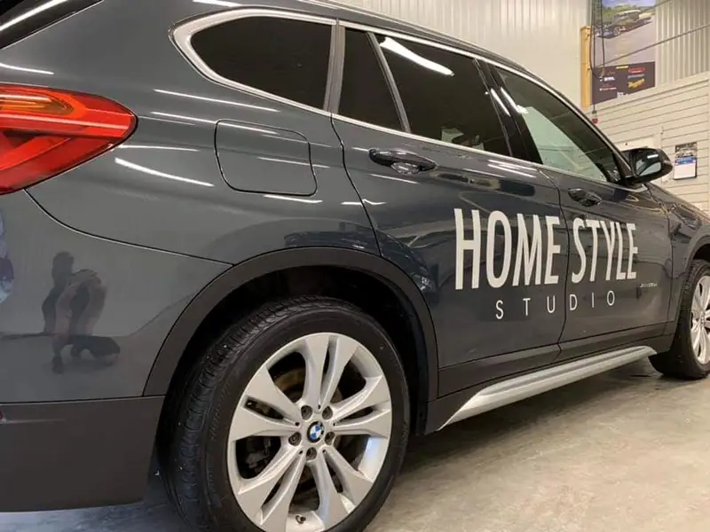 Sidan på en grå BMW X1 med dekoren Home Style Studio, i närbild i verkstaden.