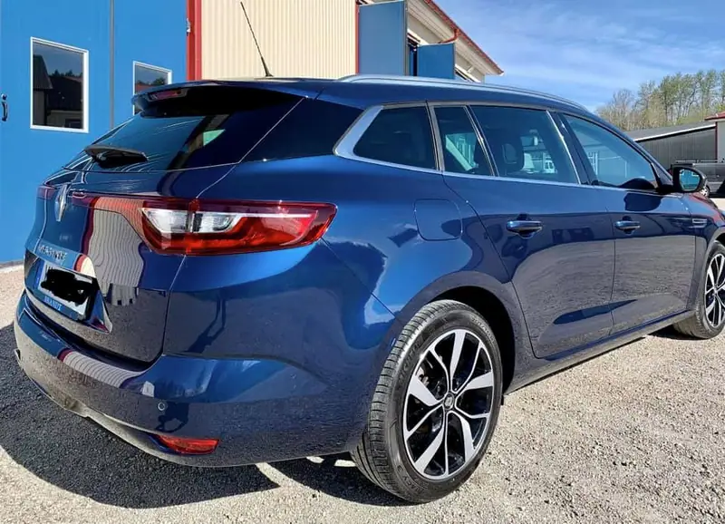 Blå Renault Mégane kombi snett bakifrån utanför verkstaden.