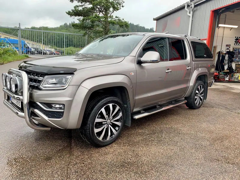 Beige Volkswagen Amarok pickup med frontbåge och extraljus utanför verkstaden.